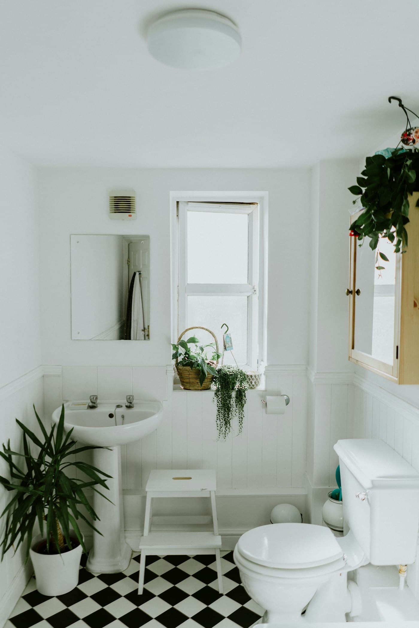 A bright white bathroom with a pedestal sink and checkerboard floor