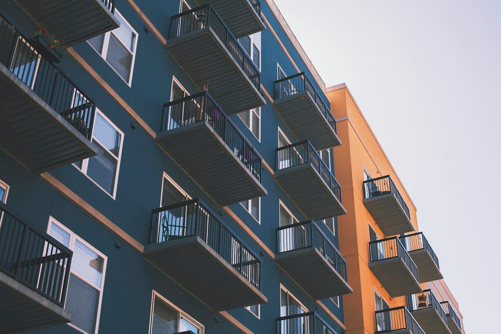 An apartment building with rows of balconies in blue and warm ochre