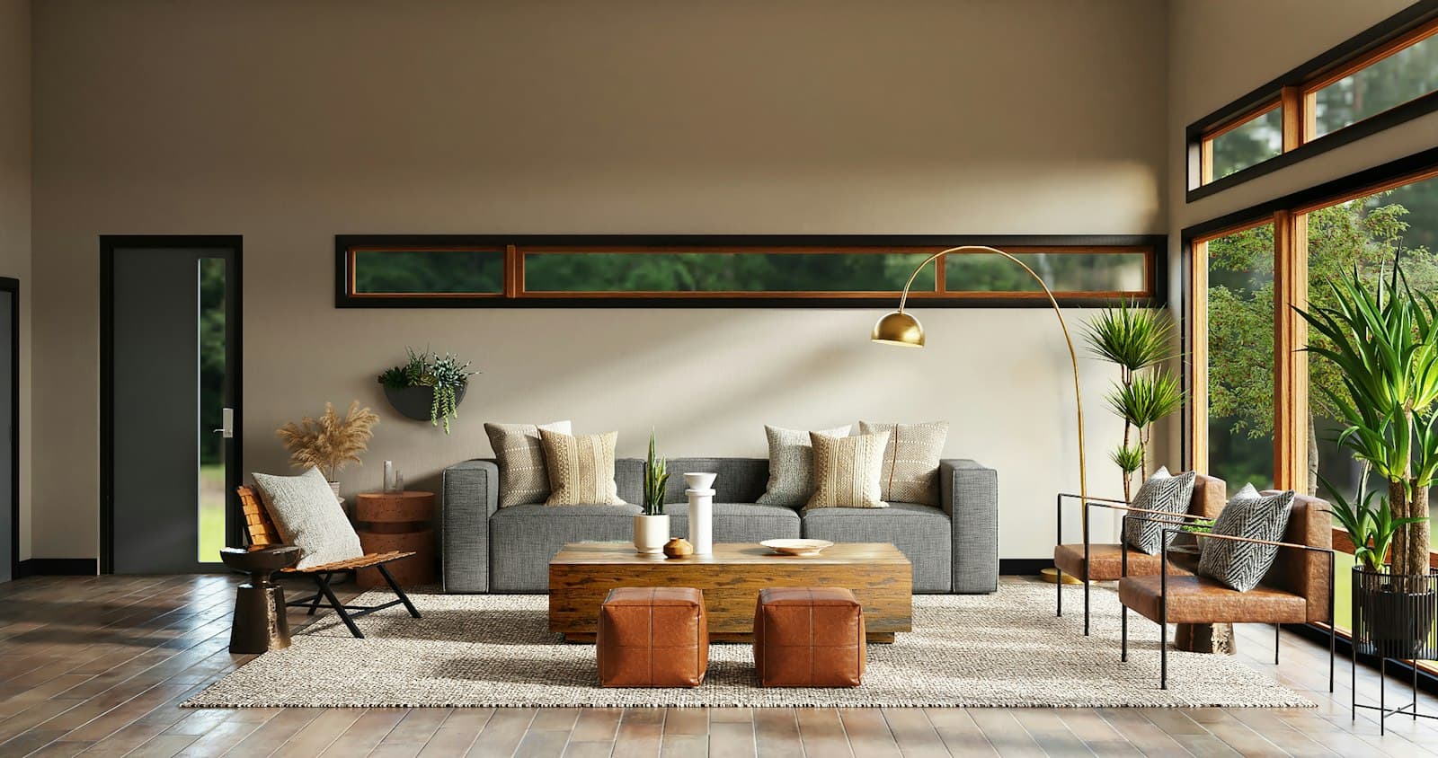 A living room with a grey sofa, leather chairs, and tall windows onto trees